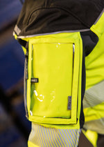 Laden Sie das Bild in den Galerie-Viewer, Hier ist eine Softshelljacke abgebildet, die winddicht und wasserabweisend ist. Eine durchdachte Taschenplatzierung ermöglicht das Tragen der Jacke im Klettergurt beim Industrieklettern in der Höhe (Ansicht Nahaufnahme Tasche links)
