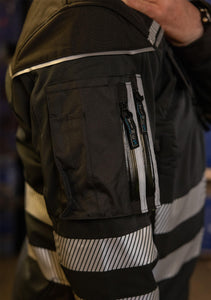 Hier ist eine Softshelljacke abgebildet, die winddicht und wasserabweisend ist. Eine durchdachte Taschenplatzierung ermöglicht das Tragen der Jacke im Klettergurt beim Industrieklettern in der Höhe (Ansicht Nahaufnahme Tasche rechts)